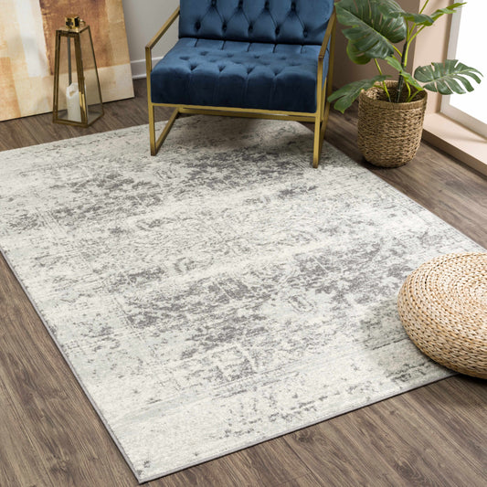 Living room with a gray and white patterned rug, blue tufted chair, and decorative items.