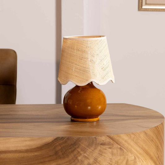 Table lamp with a brown base and beige lampshade on a wooden table.